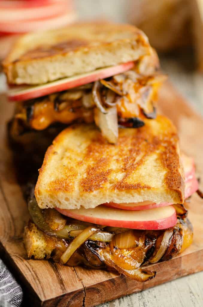 Sourdough grilled cheese with apples, balsamic onions and cheddar stacked on wood platter