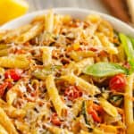 Pasta Primavera in white bowl with fresh basil, lemon and parmesan