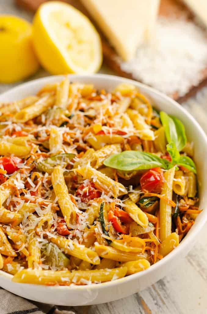 Pasta Primavera in white bowl with fresh basil and lemon