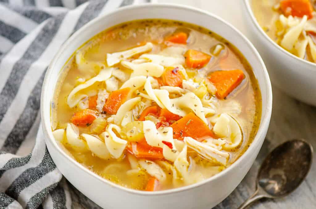 bowl of Greek chicken noodle soup in bowl with striped napkin