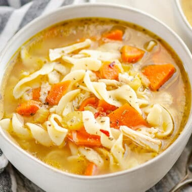 bowl of Greek chicken noodle soup in bowl with striped napkin