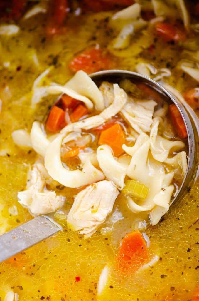 bowl of Greek chicken noodle soup in pressure cooker, scooped with ladle