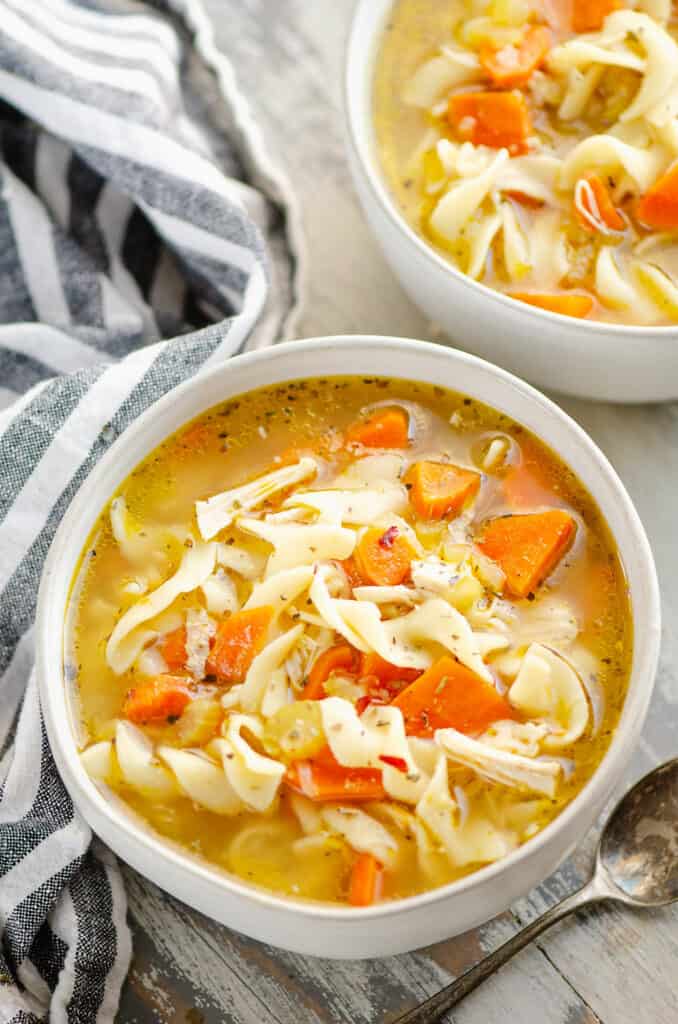 bowl of Greek chicken noodle soup in bowl on table with spoon