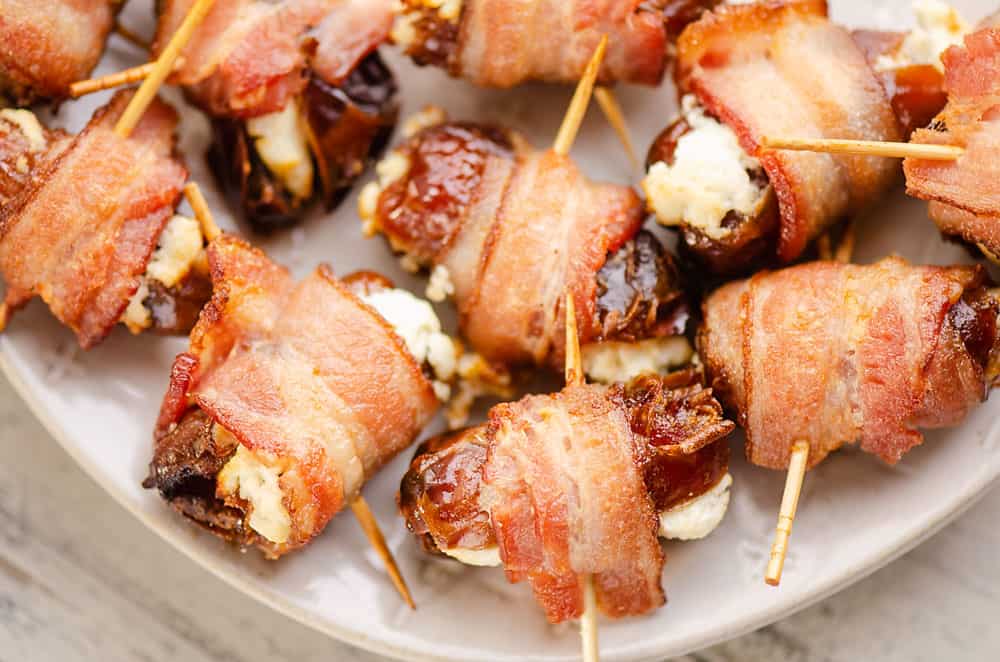 bacon wrapped goat cheese dates on white plate