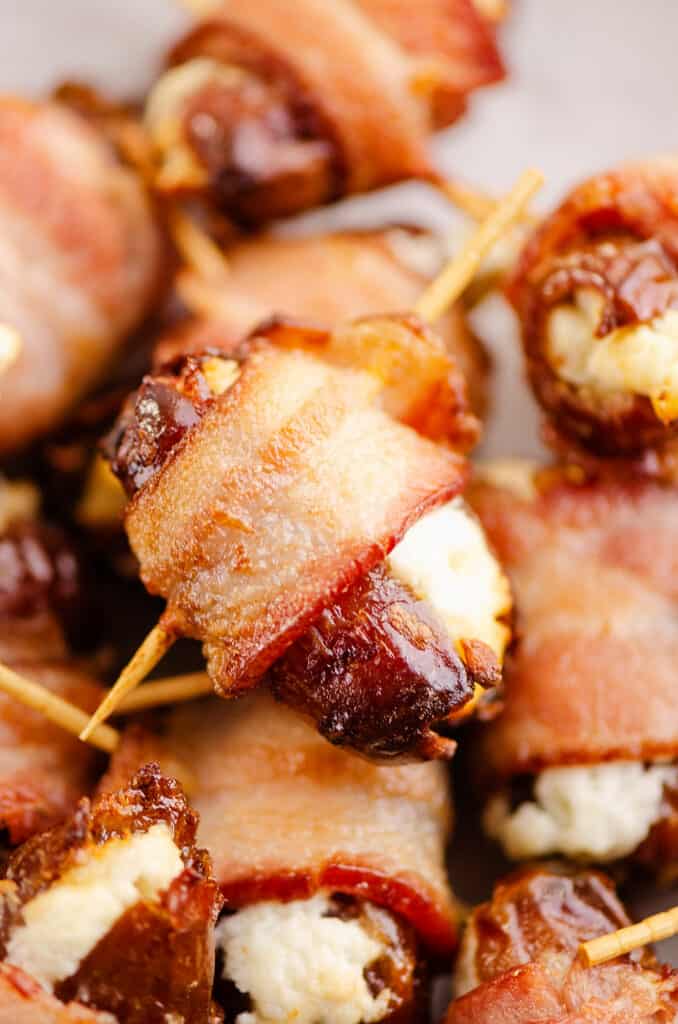 bacon wrapped goat cheese dates with toothpicks on platter