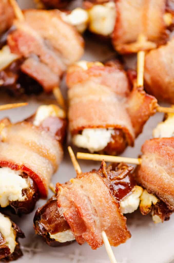 bacon wrapped goat cheese dates on white platter