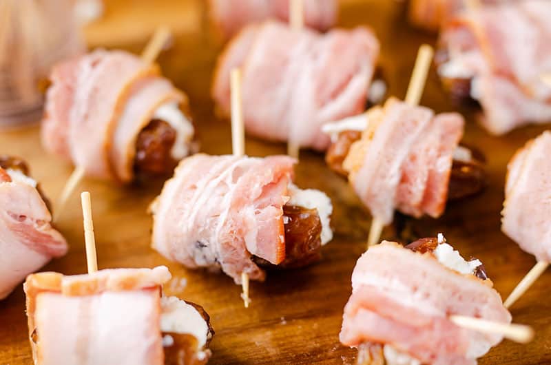 goat cheese stuffed dates wrapped with bacon and toothpick on cutting board
