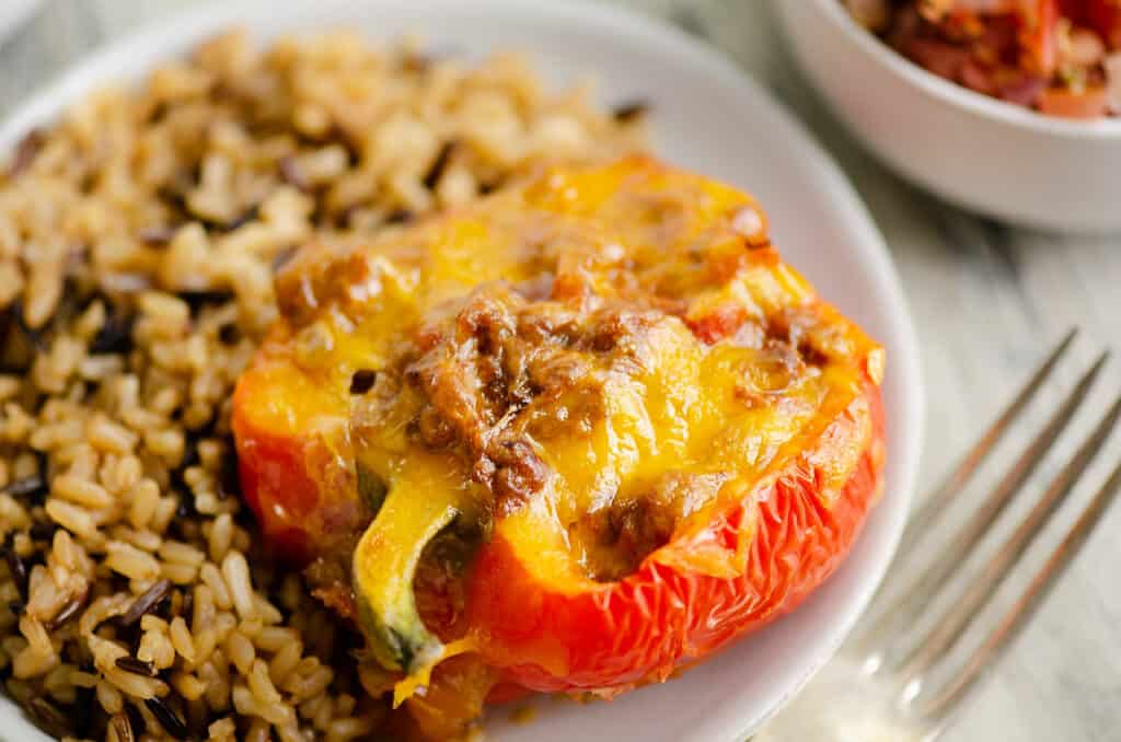 Cheesy Taco stuffed pepper on white plate with rice