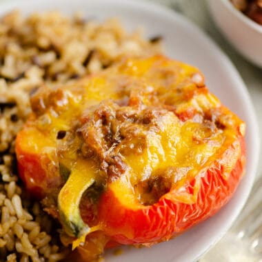 Cheesy Taco stuffed pepper on white plate with rice