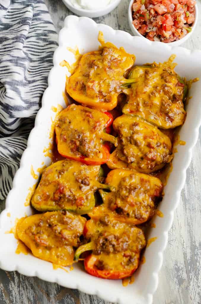 Cheesy taco stuffed bell peppers in white scalloped baking dish