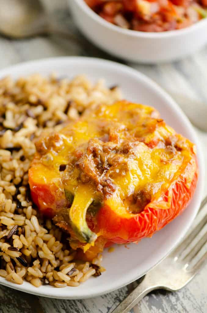 Cheesy taco stuffed pepper on shite plate with rice