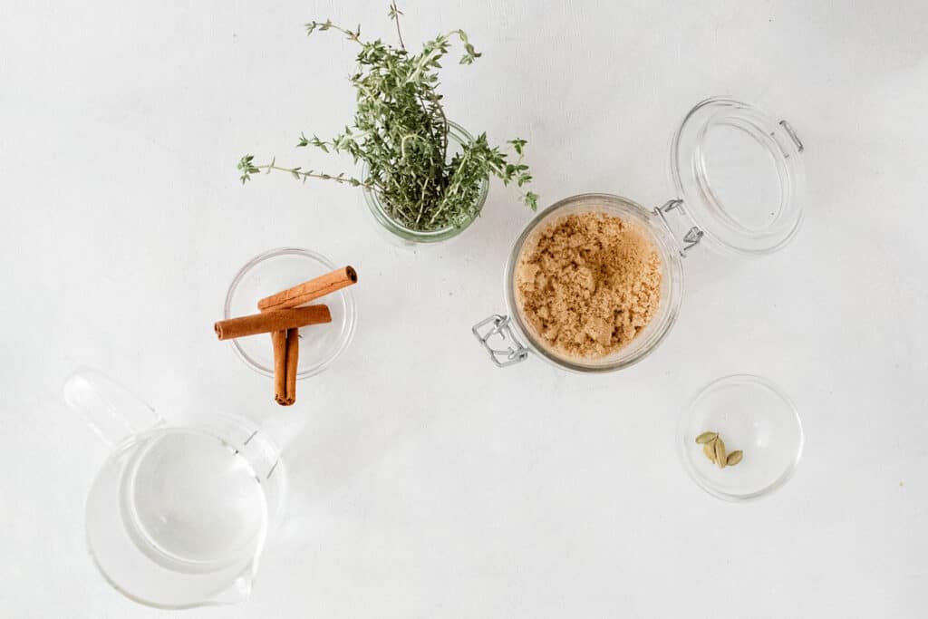 brown sugar, cinnamon sticks, thyme and cardamom on white table