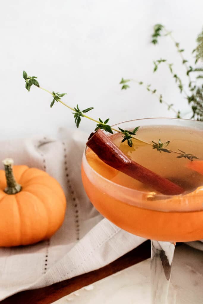 fall spiced old fashioned with cinnamon stick and thyme sprig in glass