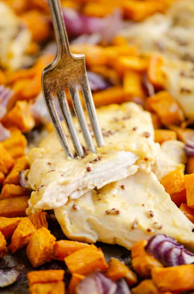 honey mustard chicken breast with fork and sweet potatoes on sheet pan