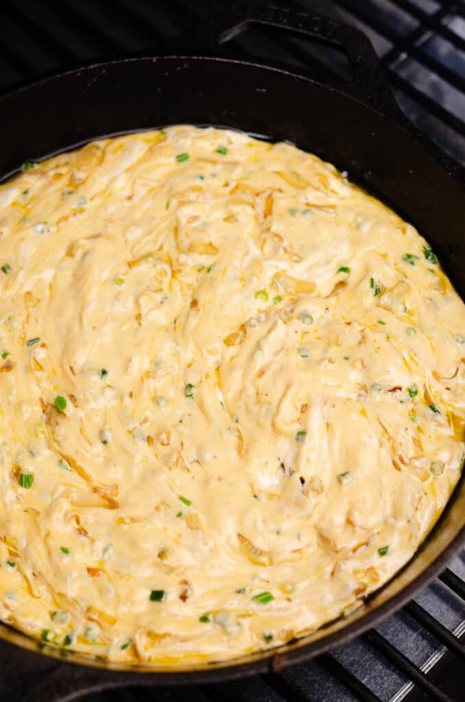cheesy caramelized onion dip in skillet on pellet smoker