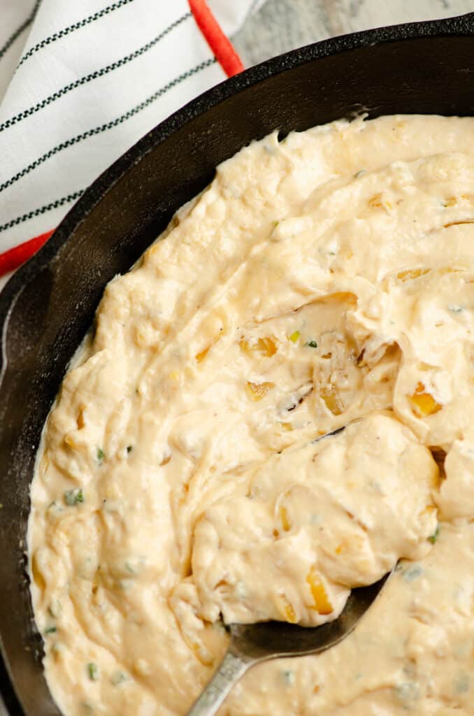 skillet with cheesy caramelized onion dip with spoon