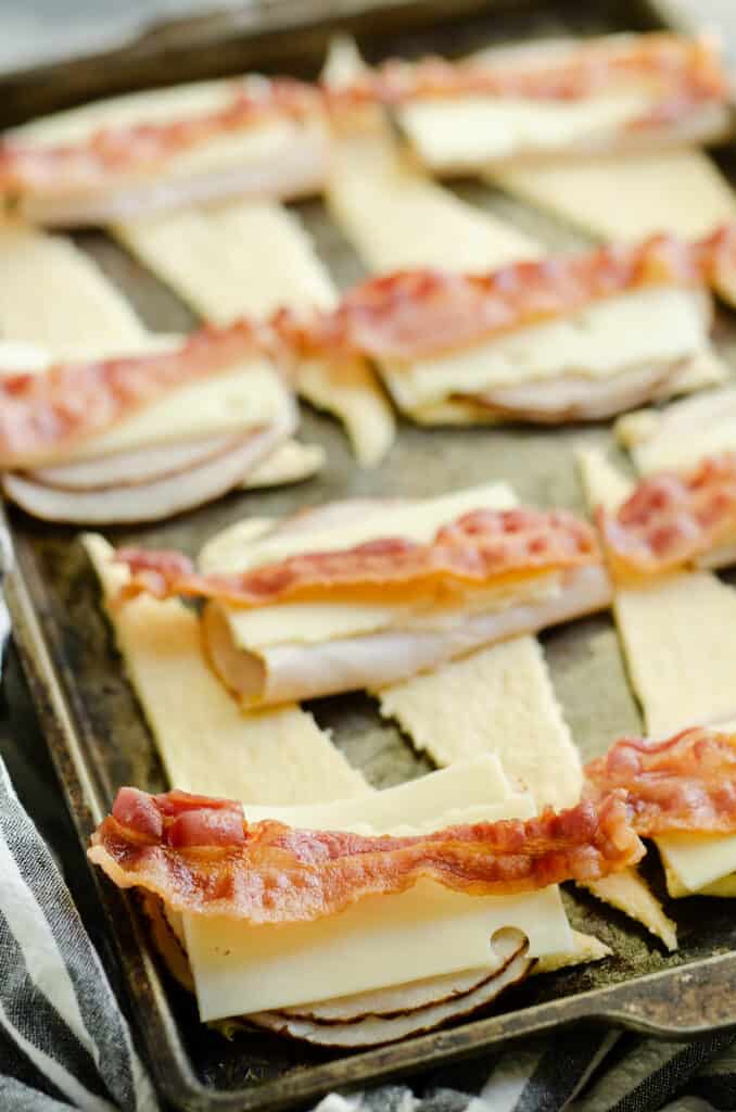 crescents on sheet pan topped with turkey, bacon and swiss cheese