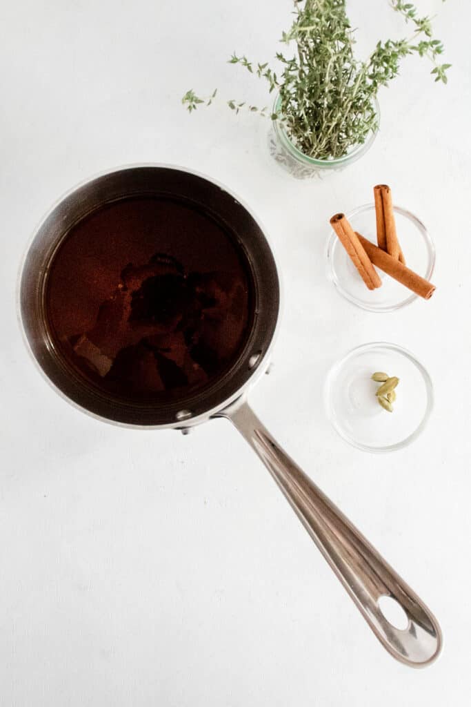 brown sugar simple syrup with cinnamon sticks and thyme on white table