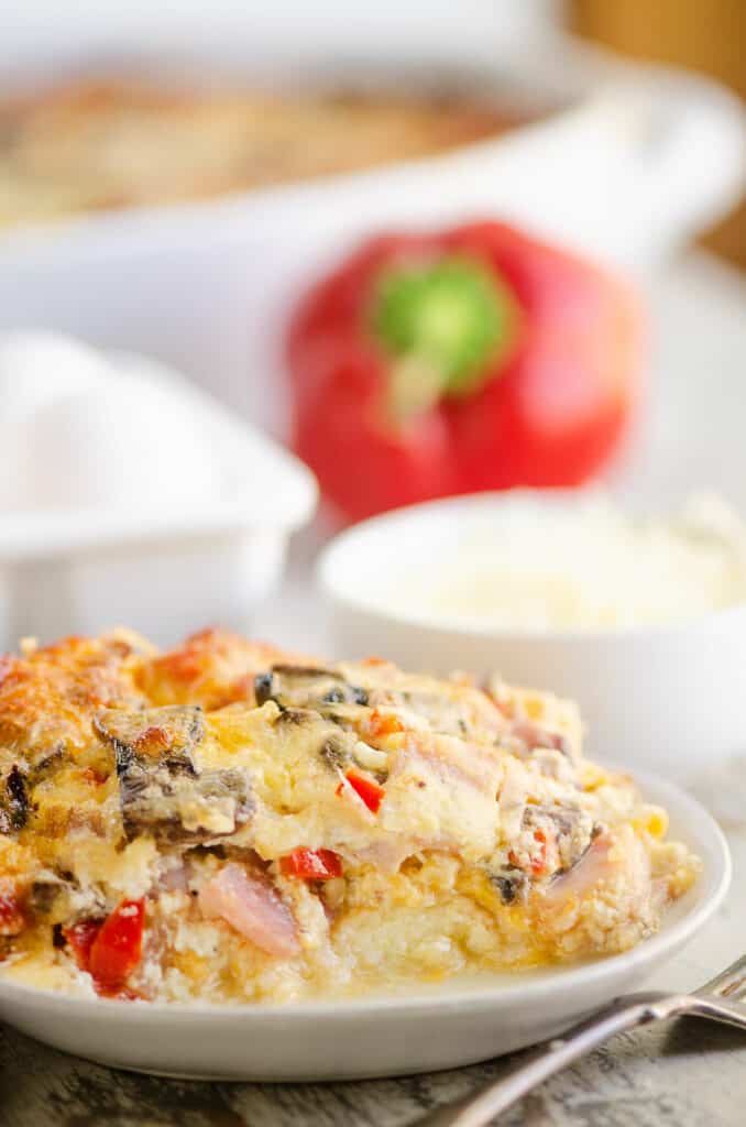 slice of ham and vegetable egg bake on table with bell pepper and eggs