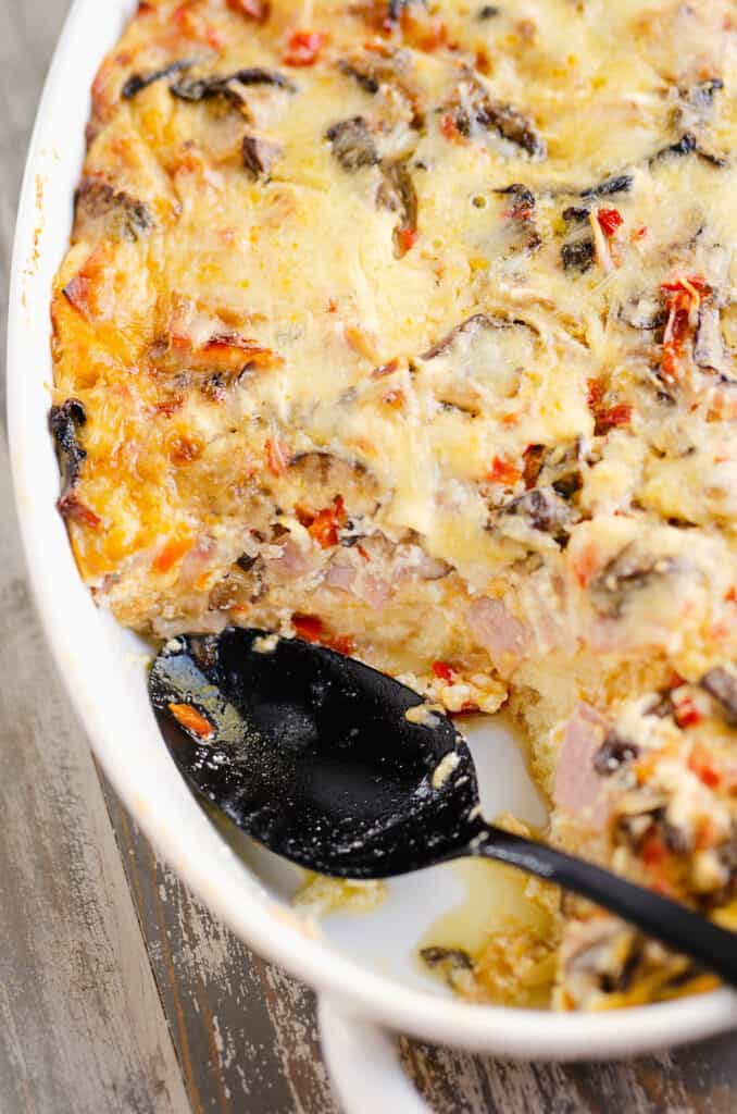 overnight ham and vegetable egg bake in white casserole with spoon