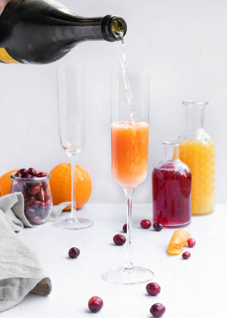 champagne poured into mimosa glass with cranberry and orange juice