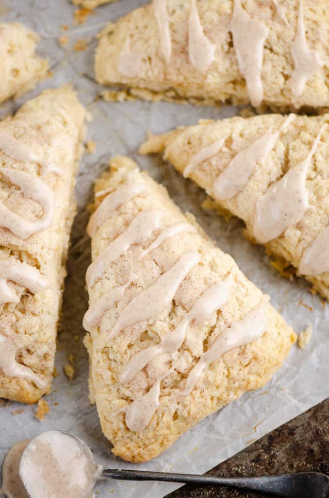 cinnamon scone on parchment drizzled with cinnamon glazed