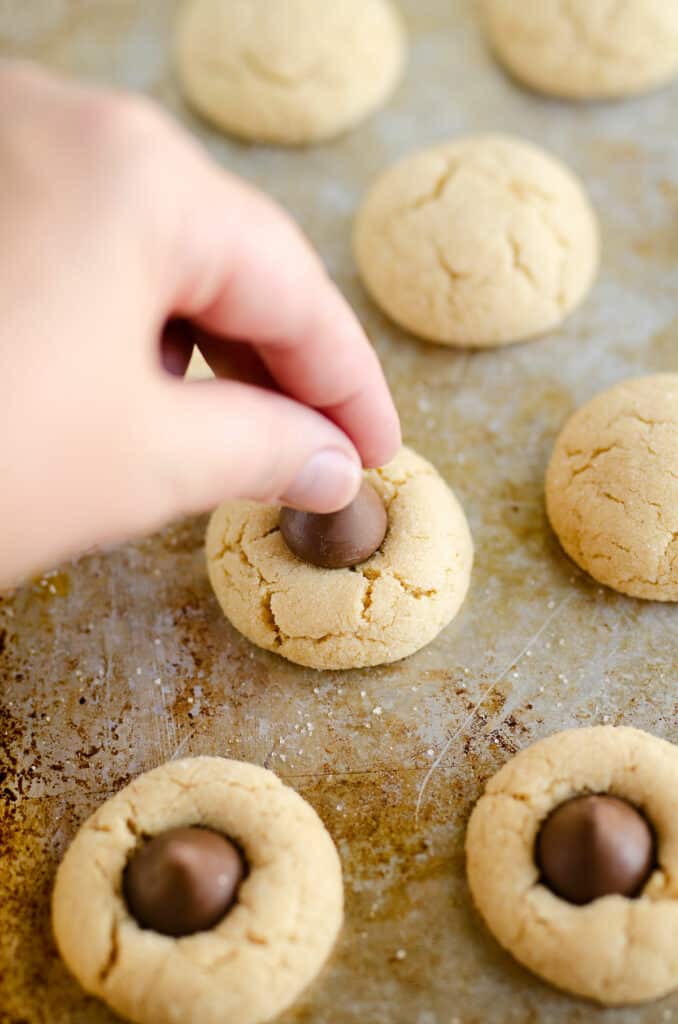 peanut butter blossom cookie being topped with hershey kiss