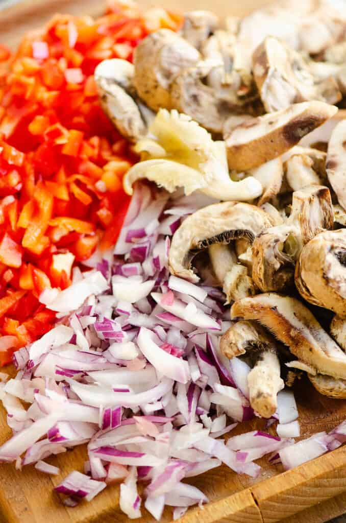 bell peppers, mushrooms and onion on cutting board