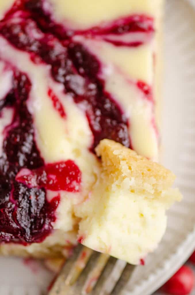 bite of cranberry cheesecake on fork with plated bar