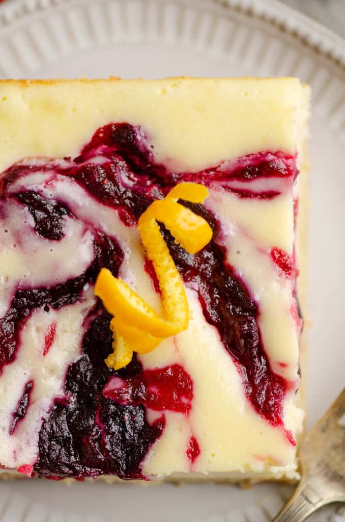 cranberry cheesecake swirl bar on plate topped with orange rind