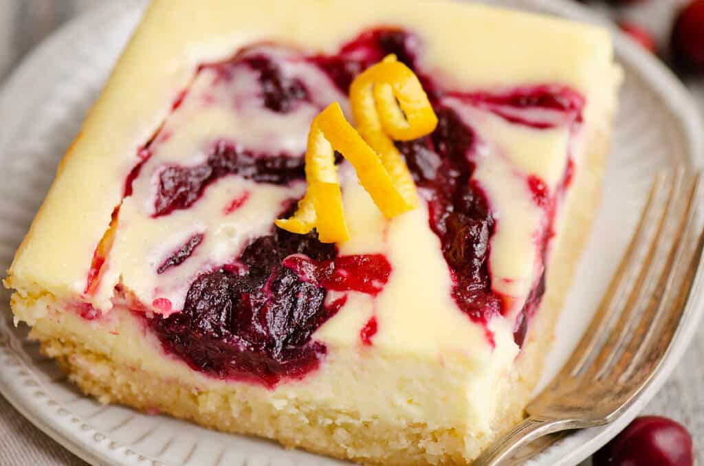 cranberry cheesecake swirl bar on plate with fork topped with orange