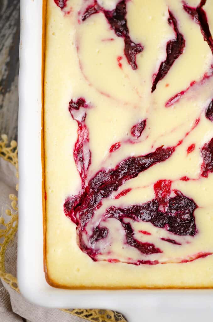 cranberry orange cheesecake swirl bars in white pan