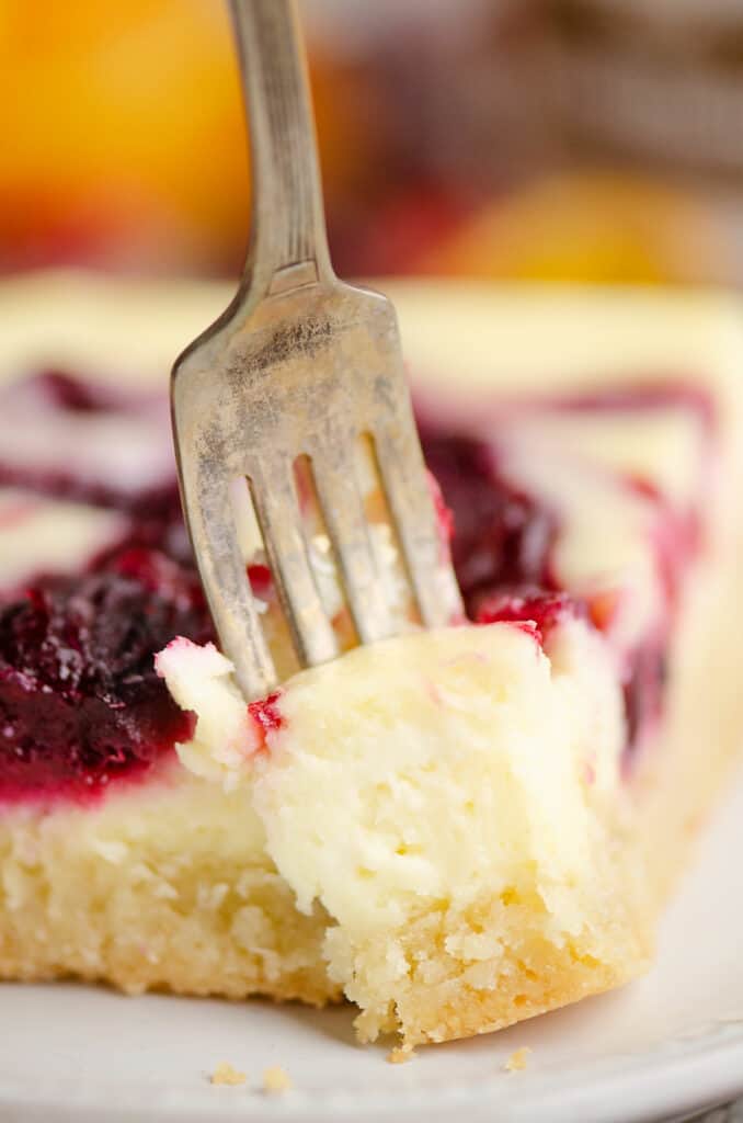 bite removed from cranberry orange cheesecake swirl bar with fork