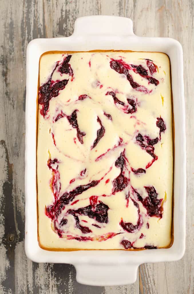 cranberry orange cheesecake swirl bars in pan on table