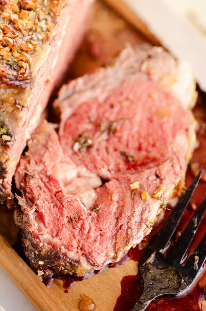 slice of garlic butter prime rib cut from roast on cutting board