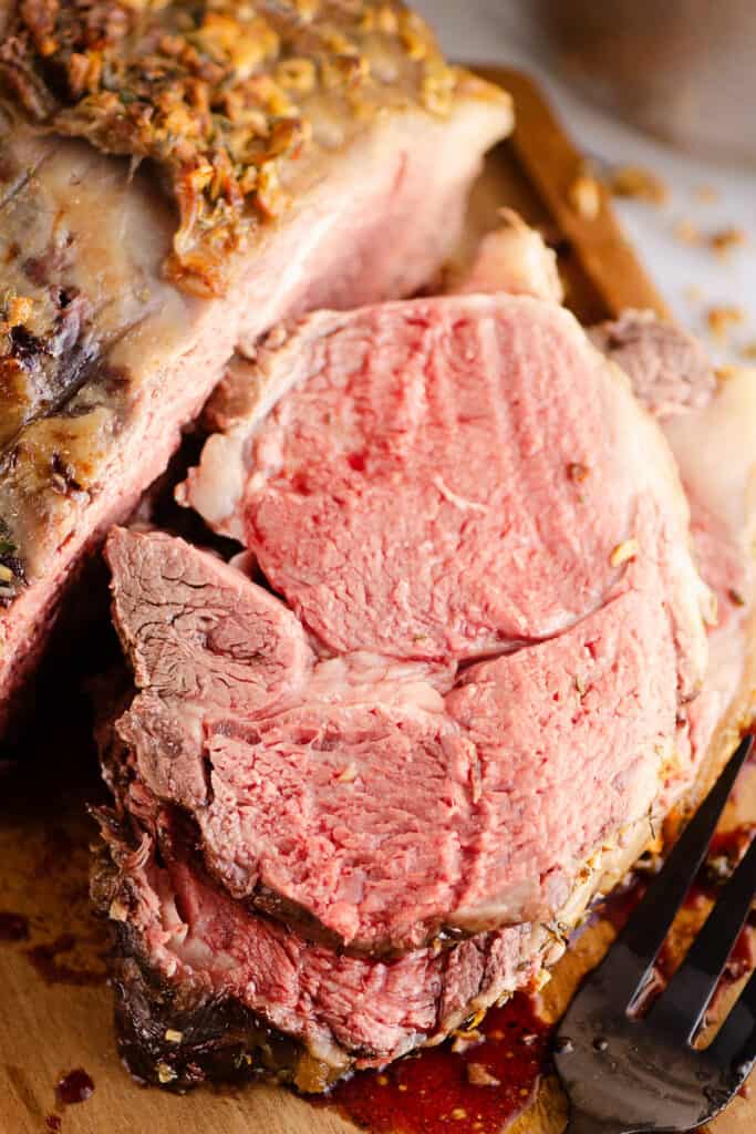 garlic butter prime rib slices stacked on cutting board
