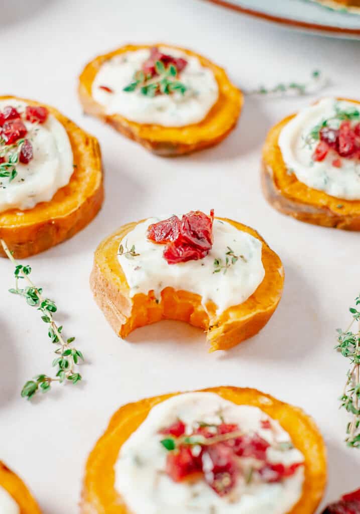 bite out of roasted sweet potato bite topped with goat cheese and cranberries