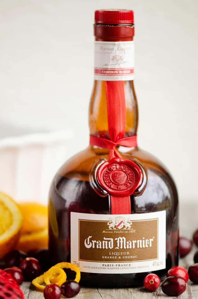 bottle of Grand Marnier on table with oranges and cranberries