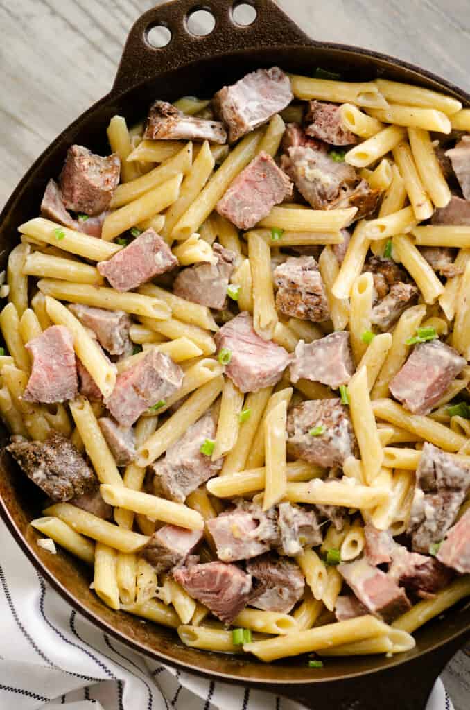leftover prime rib and penne pasta in skillet on table