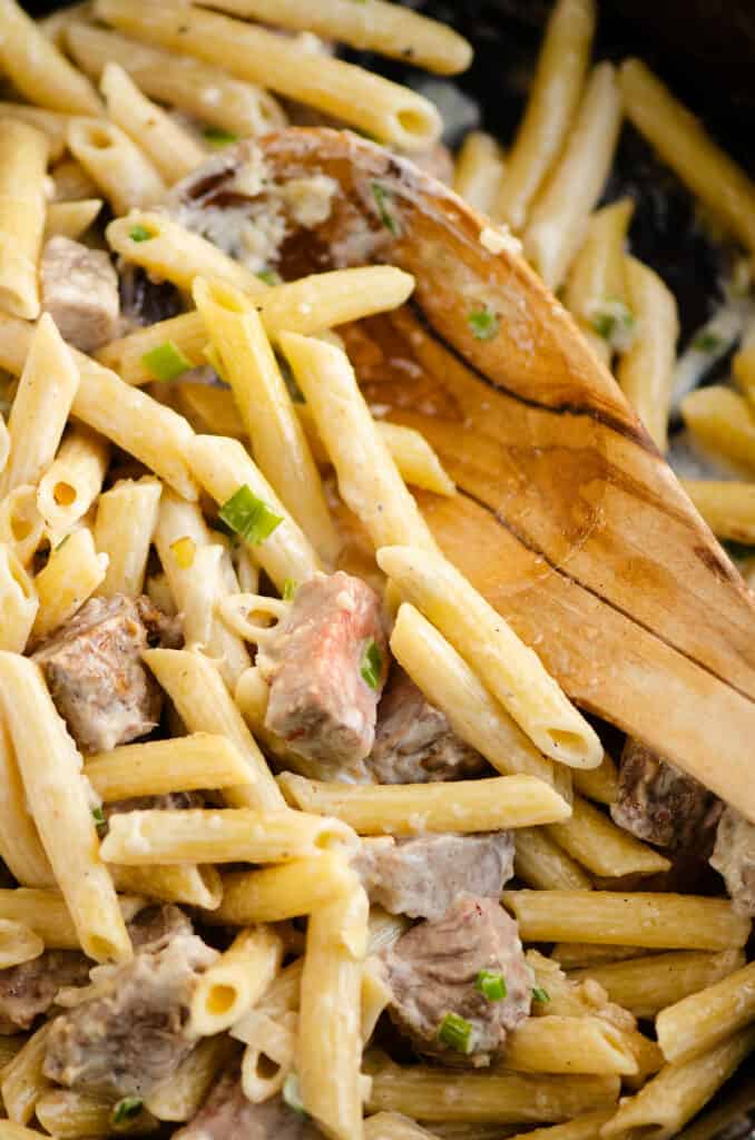 leftover prime rib and penne pasta in skillet with wooden spoon