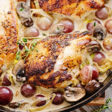 seared chicken breasts in cast iron skillet with grapes, mushrooms and white wine cream sauce