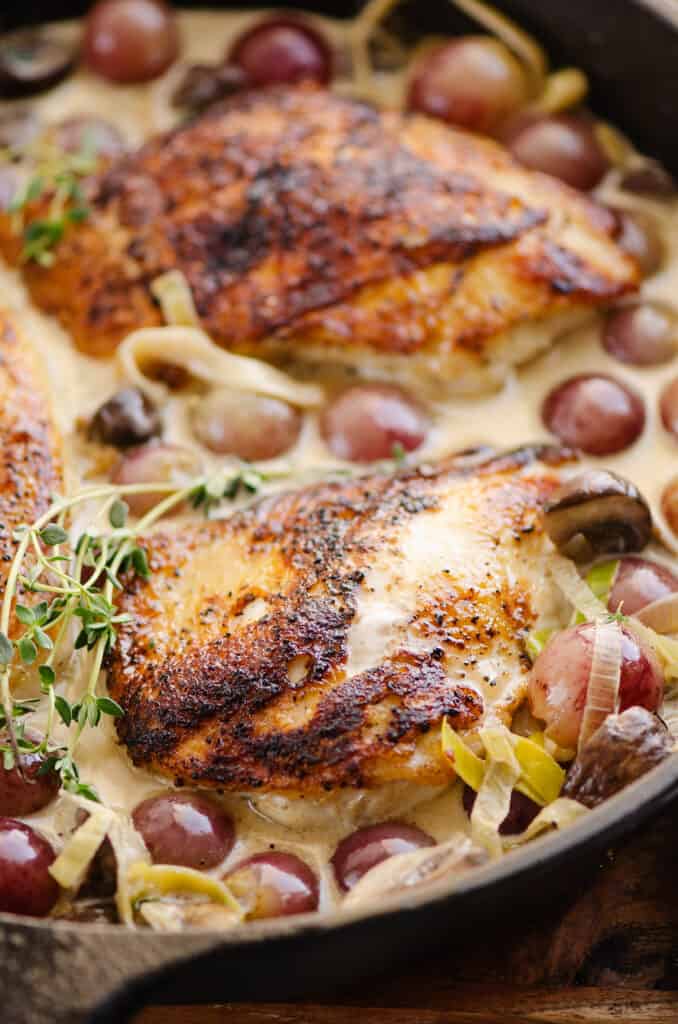 seared chicken breasts in pan with cream sauce, thyme and grapes
