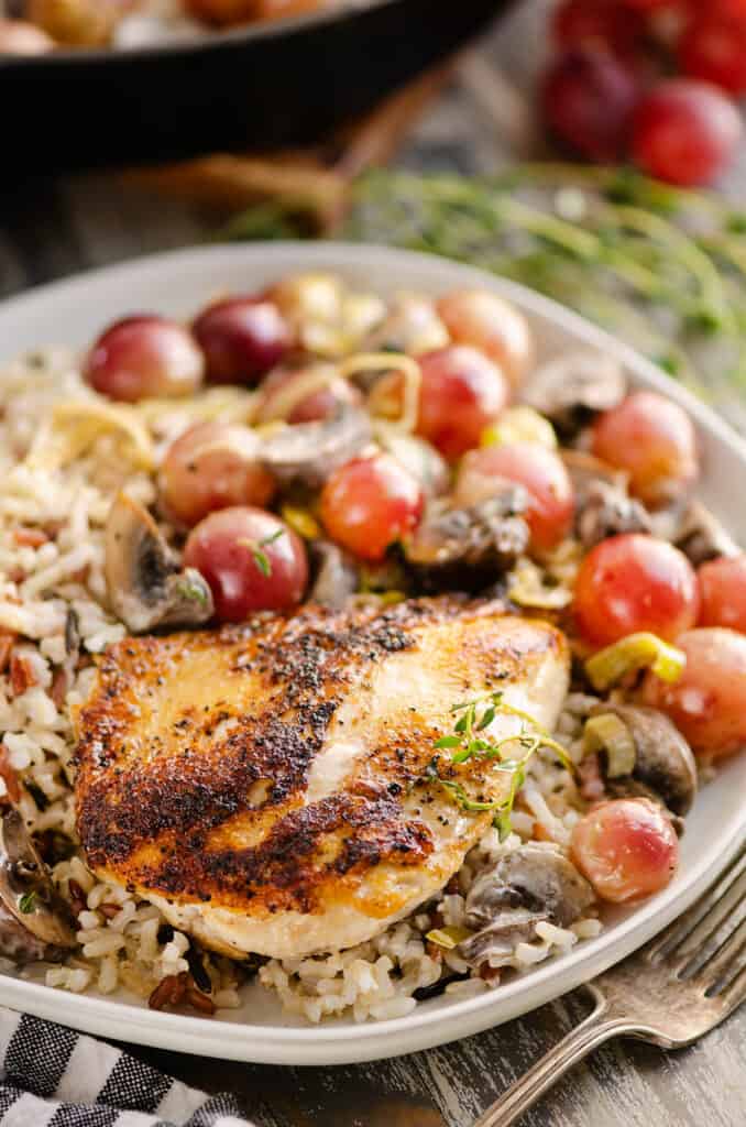 chicken breast on plate served with grapes and rice