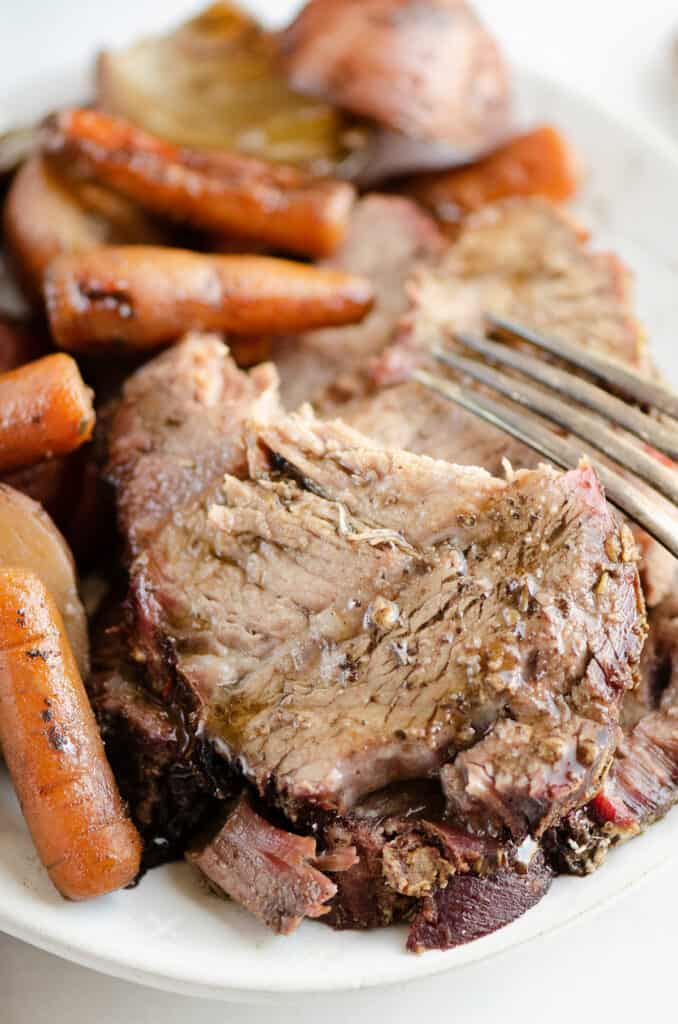 tender pot roast with vegetables on plate with fork