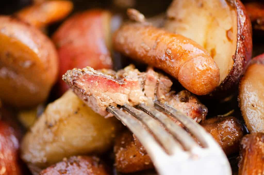 piece of pot roast with smoke ring on fork over vegetables