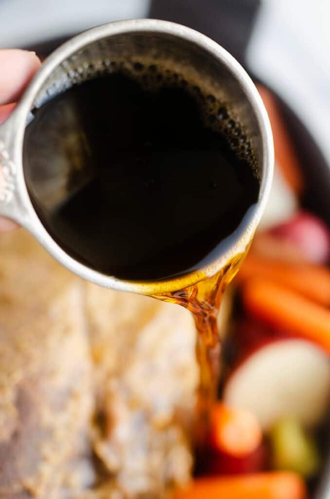 beef broth poured from measuring cup