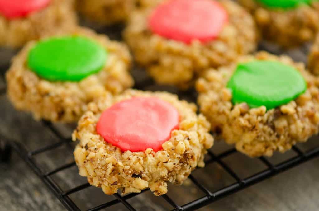 walnut thumbprint cookies with frosting on cooling wrack on table