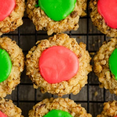 walnut thumbprint cookies with pink and green frosting on cooling rack