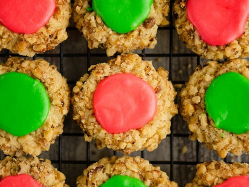 walnut thumbprint cookies with pink and green frosting on cooling rack
