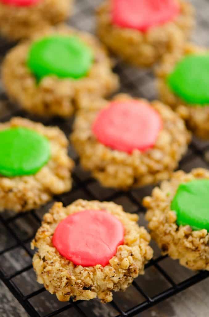 walnut thumbprint cookies with red and green frosting on cooling wrack